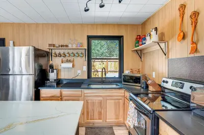 a kitchen with wooden cabinets and a stainless steel refrigerator at Patio and Hot Tub Cozy Cabin Retreat in Bailey! in Bailey