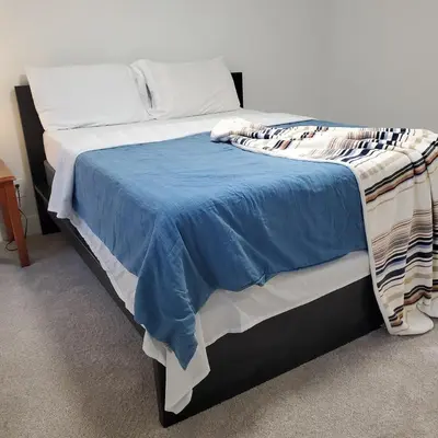 a bed with a blue blanket on top of it at 7 bedroom 8 beds family house in Denver