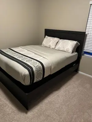 a bed with a black frame and white sheets and pillows at Humble Home in Aurora