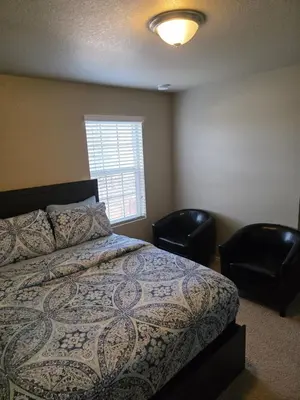 a bedroom with a bed and two chairs and a window at Humble Home in Aurora