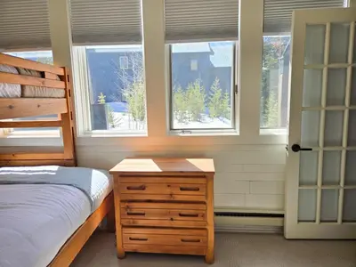 a bedroom with a bed and a dresser and windows at The Rail Haven townhouse in Winter Park
