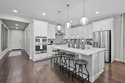 a kitchen with white cabinets and a island with bar stools at Ouray Street - Commerce City in Henderson