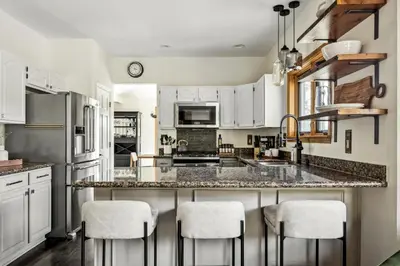 a kitchen with white cabinets and a counter with stools at Hot Tub - Scenic Views - Spacious Deck - Game Room in Evergreen