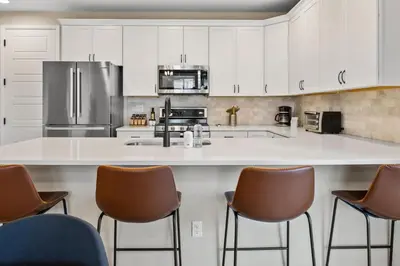 a kitchen with a large white counter with brown chairs at Sunny & Quaint Hidden Gem w Office - Dog Friendly in Westminster