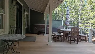 a porch with a table and chairs on a house at Rocky Mountain Retreat home in Nederland