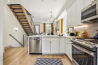 a kitchen with white cabinets and a staircase at Roof Deck - MTN View - Hot Tub - Cold Plunge in Silverthorne