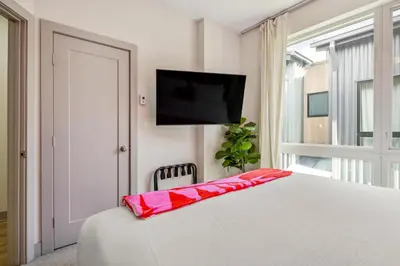 a bedroom with a white bed with a television on the wall at Roof Deck - MTN View - Hot Tub - Cold Plunge in Silverthorne