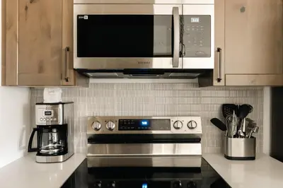 a kitchen with a microwave and a stove top oven at New Luxe Condo - Hot Tub - Minutes to WP! - Fraser in Fraser