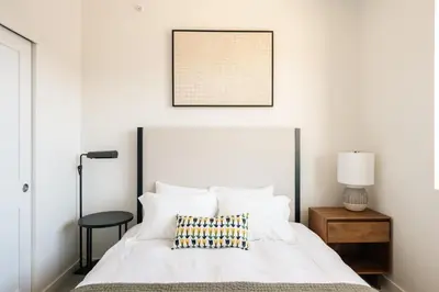 a bedroom with a white bed with a picture on the wall at Chic Condo - Near Town and Trails - Hot Tub - Deck in Fraser