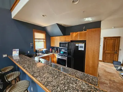 a kitchen with a black refrigerator and wooden cabinets at 2 BR, 2 BA Mountain View Family Friendly Condo BCA-45499 in Keystone