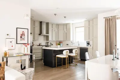 a kitchen with white cabinets and a kitchen island with bar stools at Vogue Posh Pad - Center of LoHi - Large Roof Deck in Denver