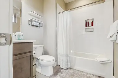a white bathroom with a toilet and a bath tub at Serene Escape in Fraser in Fraser