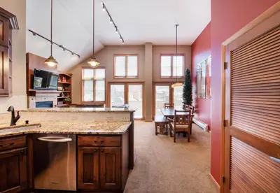 a kitchen with a counter and a dining room at Select Unit 1710 - 2BR - Zephyr Mountain Lodge condo in Winter Park