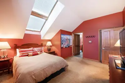 a bedroom with a bed with red walls and a skylight at Select Unit 1710 - 2BR - Zephyr Mountain Lodge condo in Winter Park