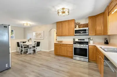 a kitchen with wooden cabinets and a table with a dining room at Downtown Windsor Home with Hot Tub and Pool Table in Windsor