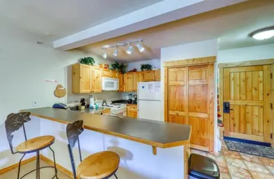 a kitchen with wooden cabinets and a counter with chairs at Tenderfoot Lodge 1 Bedroom At The Mountain House Base in Keystone