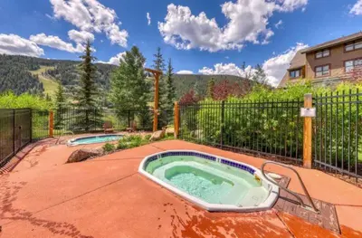 a hot tub in a patio with a fence at Tenderfoot Lodge 1 Bedroom At The Mountain House Base in Keystone