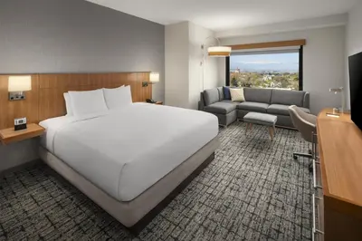 a bedroom with a large white bed and a couch at Hyatt Place Denver Cherry Creek in Denver