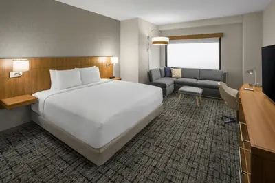 a hotel room with a large white bed and a couch at Hyatt Place Denver Cherry Creek in Denver