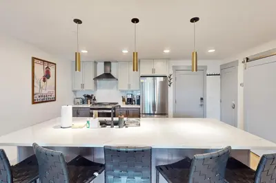 a kitchen with white cabinets and a large island with chairs at Timber Fox Escape in Winter Park