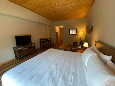 a bedroom with a large white bed and a living room at Gateway Lodge 5003 by SummitCove Lodging in Keystone
