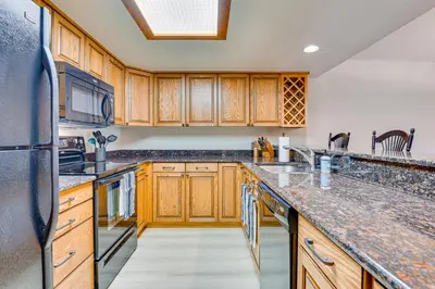 a kitchen with wooden cabinets and a black refrigerator at Steps to Shadow Mountain Lake Grand Lake Condo in Grand Lake