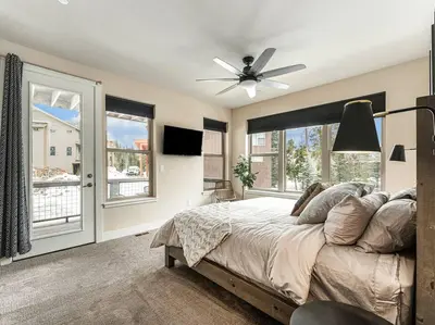 a bedroom with a bed with a ceiling fan and windows at Rendezvous - 99 Stagecoach in Fraser