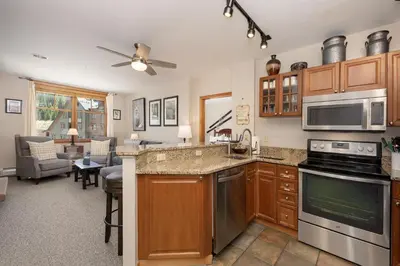 a kitchen with stainless steel appliances and a living room at Value Unit 1422 - 2BR - Zephyr Mountain Lodge condo in Winter Park