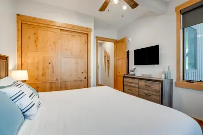 a bedroom with a white bed and a television at Modern Elk Creek Condo with Hot Tub and Heated Floors in Fraser