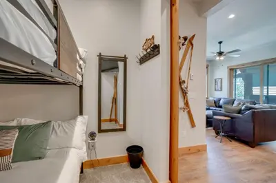 a bedroom with a bunk bed and a living room at Modern Elk Creek Condo with Hot Tub and Heated Floors in Fraser