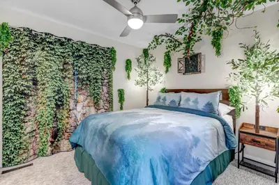 a bedroom with a bed and a wall with plants at Immersive Spa Retreat with Sauna & 15m to Red Rocks in Lakewood