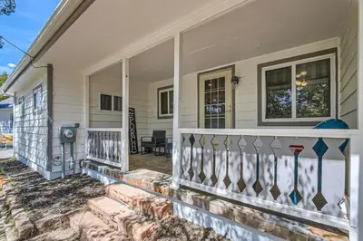 a white house with a porch with a fence at Golden Gate Getaway home in Black Hawk