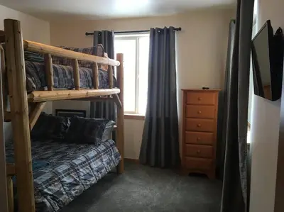 a bedroom with bunk beds and a dresser and a window at Large Winter Park Condo overlooking Hideaway Park! in Hideaway Park