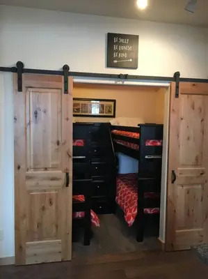 a bedroom with a bunk bed with wooden doors at Large Winter Park Condo overlooking Hideaway Park! in Hideaway Park