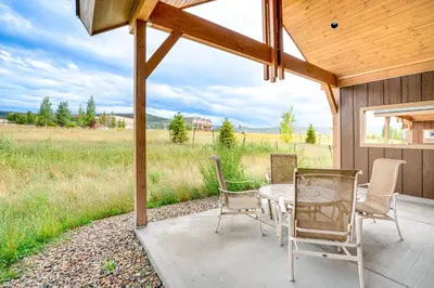 a patio with a table and chairs and a field at Private Hot Tub and Patio Granby Mtn Retreat! in Granby