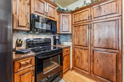 a kitchen with wooden cabinets and a stove top oven at Mountain Escape with Hot Tub Near Ski Resorts and I 70 in Silverthorne