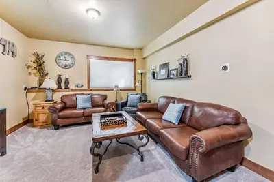 a living room with leather furniture and a clock at Mountain Escape with Hot Tub Near Ski Resorts and I 70 in Silverthorne