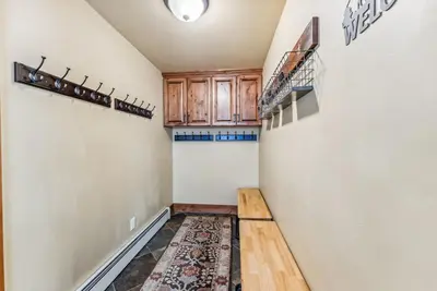 a hallway with a staircase and a kitchen with wooden cabinets at Mountain Escape with Hot Tub Near Ski Resorts and I 70 in Silverthorne