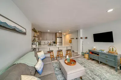 a living room with a couch and a kitchen at Ski Retreat with Hot Tub Access in Winter Park! in Winter Park
