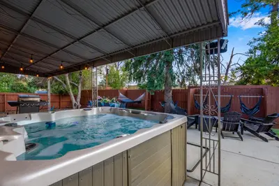 a hot tub on a patio with a deck with chairs at Mid Summer Night's Dream w Hot Tub Theater Game Room in Arvada