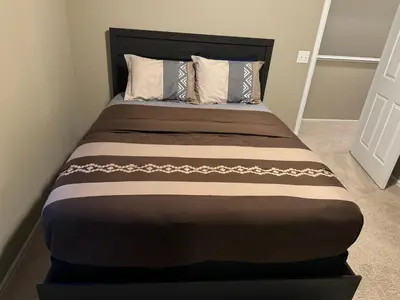 a bed in a bedroom with a brown bedspread at Humble Home in Aurora