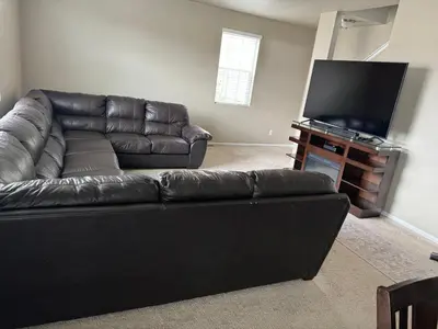 a living room with a leather couch and a flat screen tv at Humble Home in Aurora