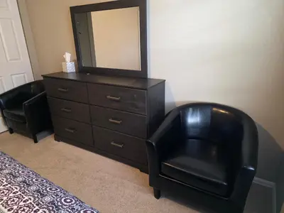 a black dresser with a mirror and a black chair at Humble Home in Aurora