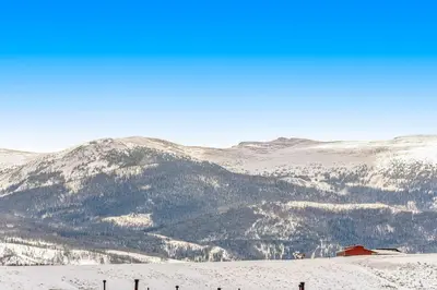 a snow covered mountain with a house in the foreground at Mallard Retreat in Tabernash