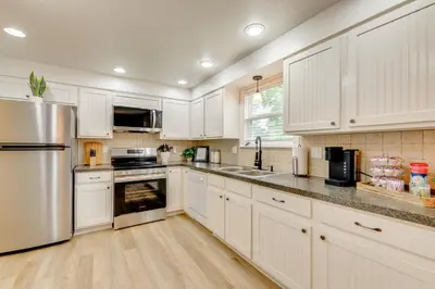 a kitchen with white cabinets and a stainless steel refrigerator at Loveland Retreat Near Dtwn with Outdoor Dining! in Loveland
