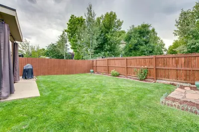 a backyard with a wooden fence and green grass at Loveland Retreat Near Dtwn with Outdoor Dining! in Loveland