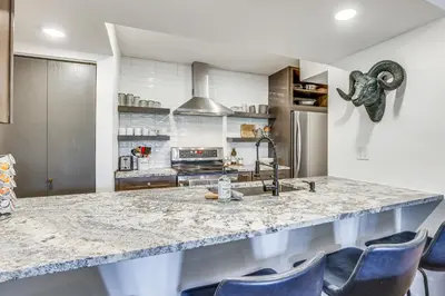 a kitchen with a large marble counter and blue chairs at Patio and Dillon Reservoir Views Chic Frisco Condo! in Frisco