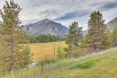 a field with trees and a mountain in the background at Patio and Dillon Reservoir Views Chic Frisco Condo! in Frisco