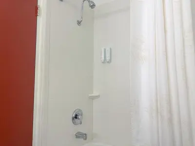 a shower with a white shower curtain next to a toilet at Quality Inn & Suites Fort Collins East in Fort Collins