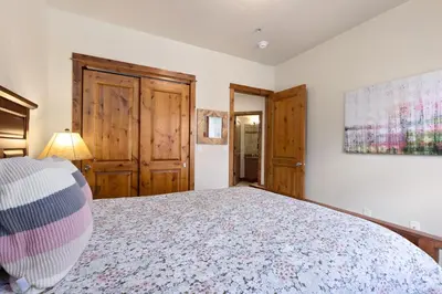 a bedroom with a large bed and wooden doors at Antlers Gulch Retreat townhouse in Keystone